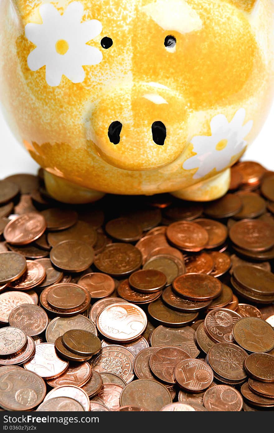 Yellow ceramic piggy bank on a pile of cents