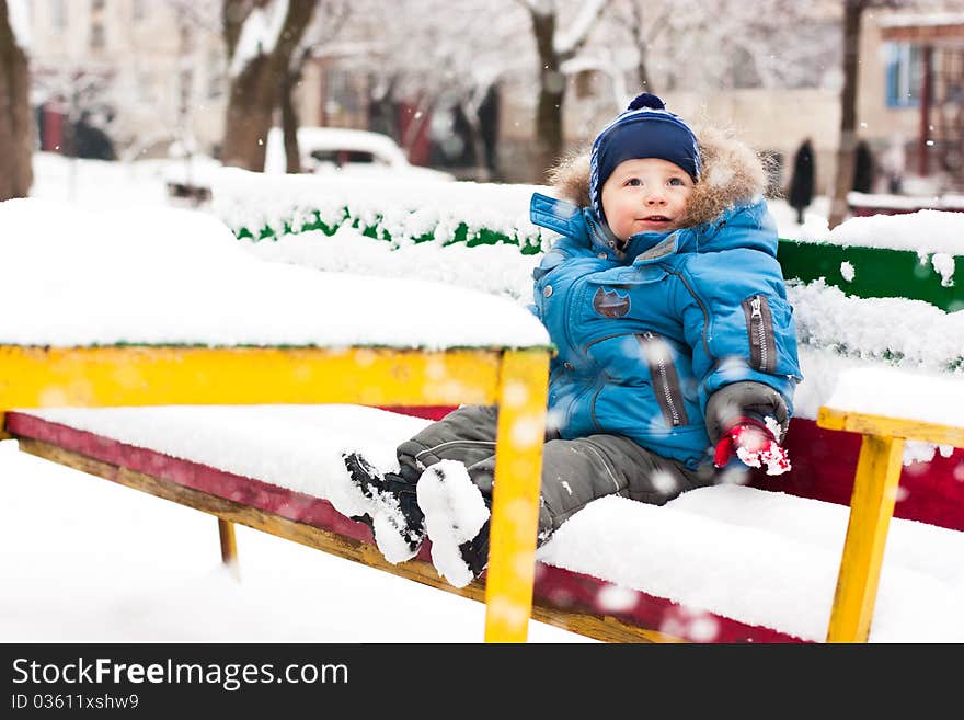 Cute Boy Sitting In Snow Outdoor