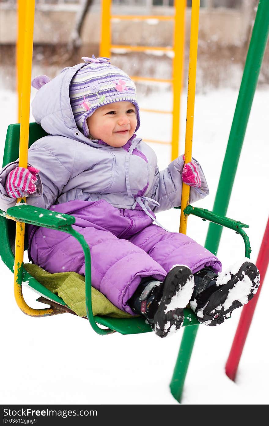 Beautiful girl sitting on a swing outdoor in snow in winter