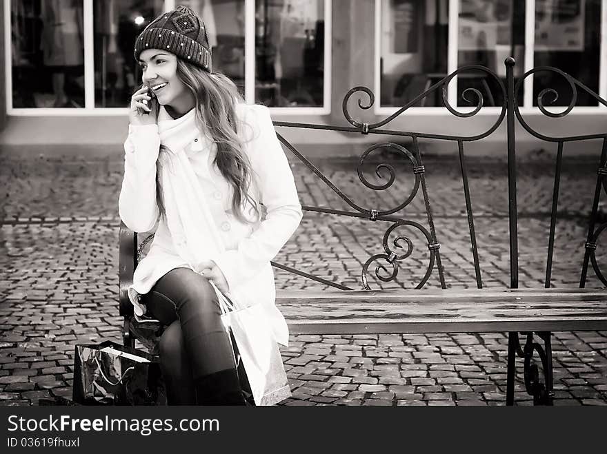 Young smiling woman sitting on berm calling with mobile phone