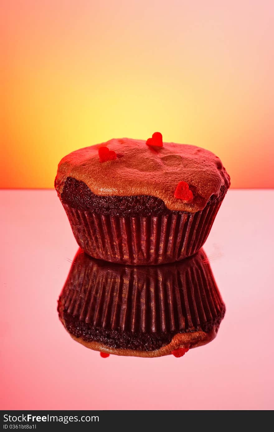 Sweet cupcake for St. Valentine day with hearts on it and reflection on red background. Sweet cupcake for St. Valentine day with hearts on it and reflection on red background