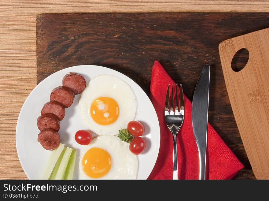 Fried eggs with fried sausage and vegetables.