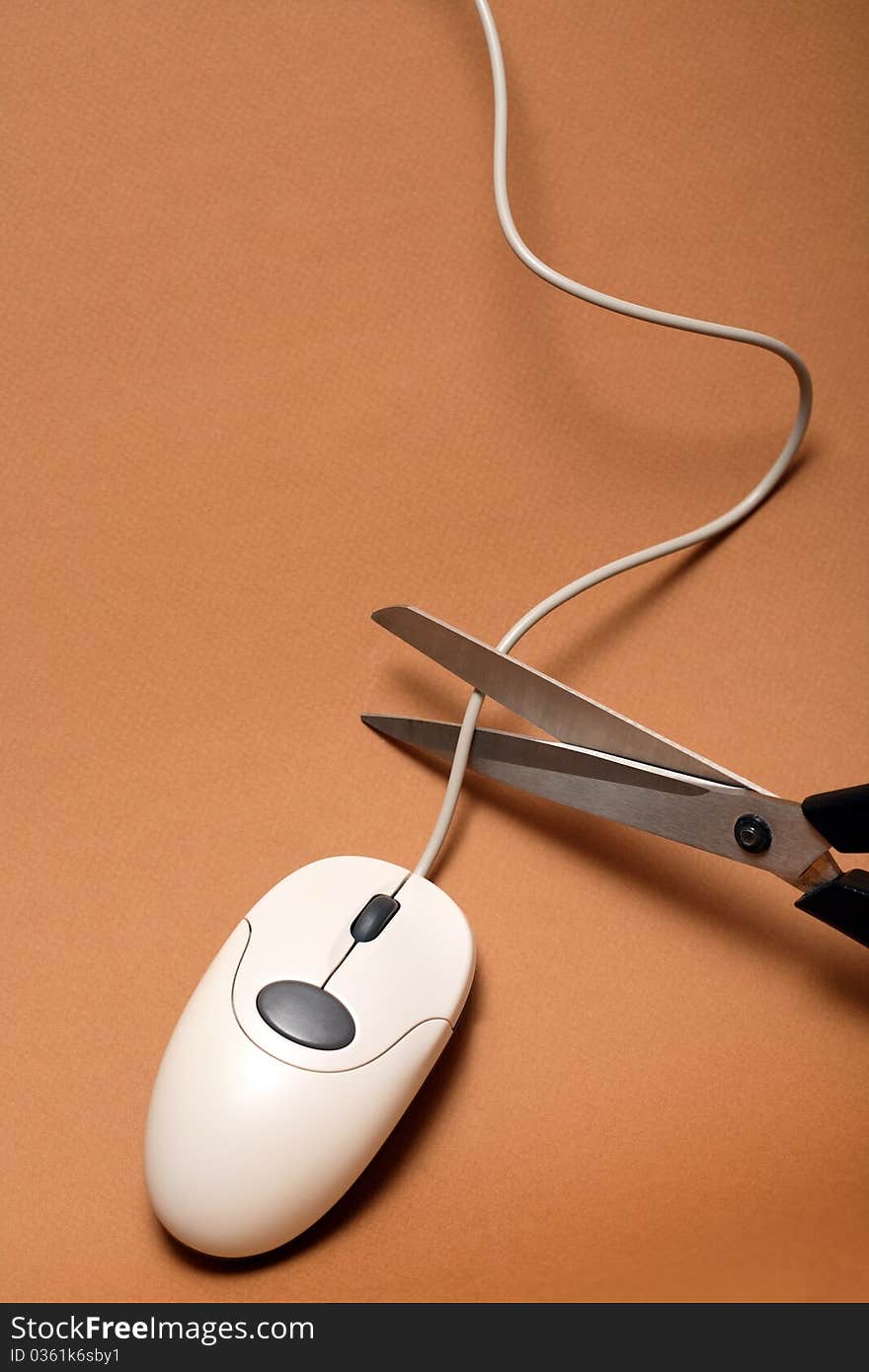 Scissors cutting cable of computer mouse on brown background. Scissors cutting cable of computer mouse on brown background