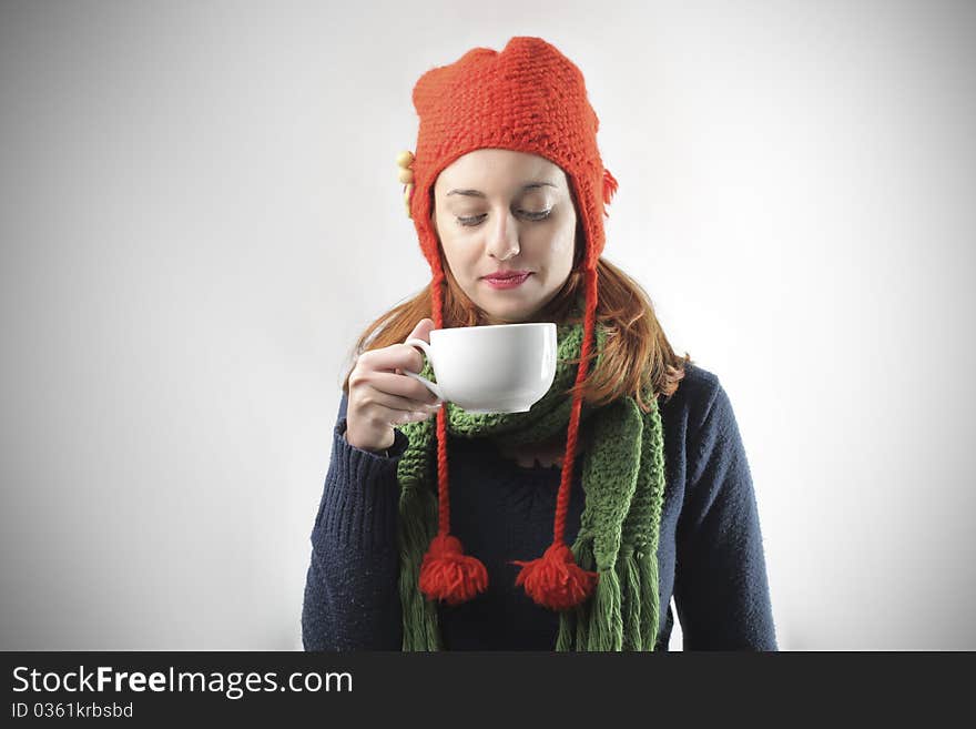 Young woman in winter clothes holding a bowl of hot drink