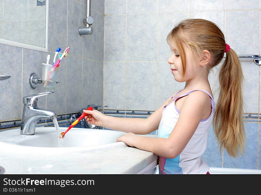 Little girl with toothbrush in the bathroom