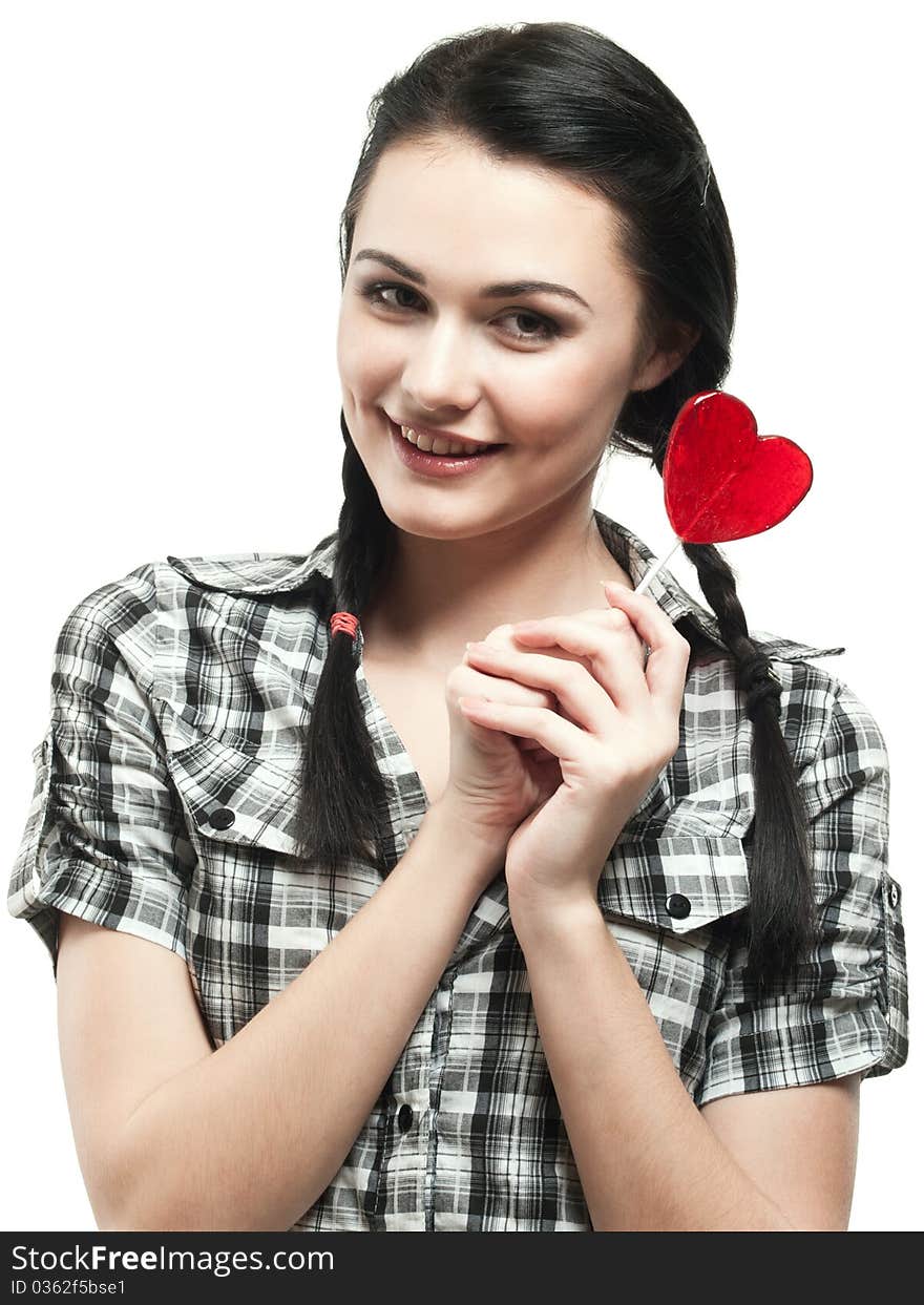 Young smiling girl with red heart lolipop isolated on white