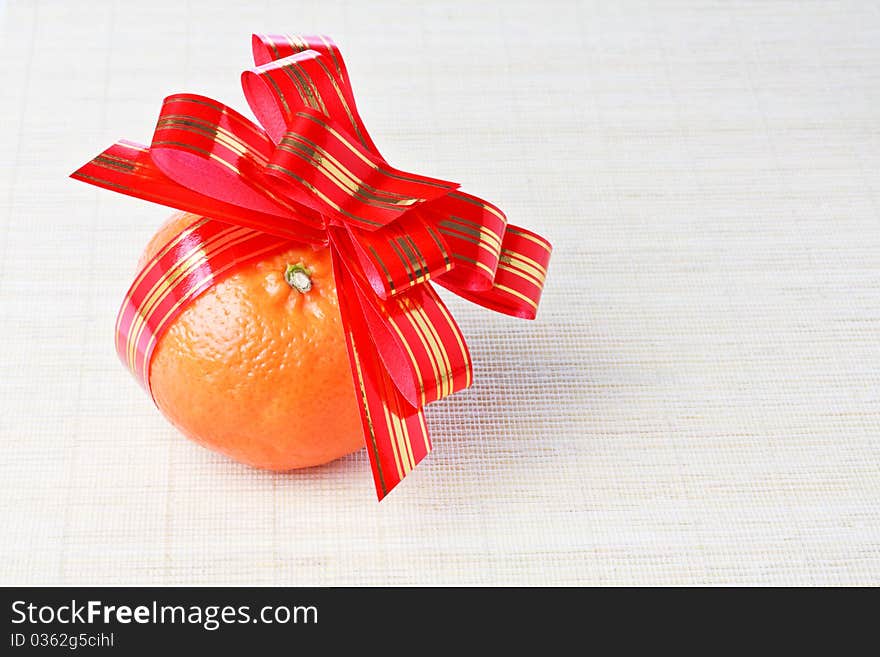 Tangerine with red goldish striped bow as a gift