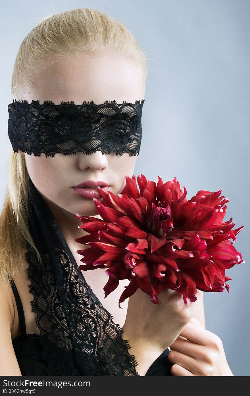 Emotional blonde girl with closed eyes and red flower at hand. Emotional blonde girl with closed eyes and red flower at hand