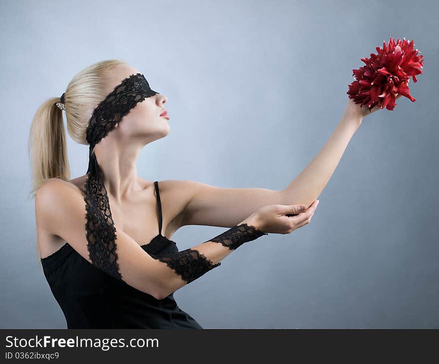 Emotional blonde girl with closed eyes and red flower at hand. Emotional blonde girl with closed eyes and red flower at hand