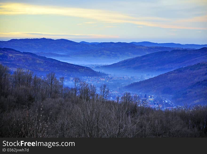 Fog over large valley village under sunny winter day