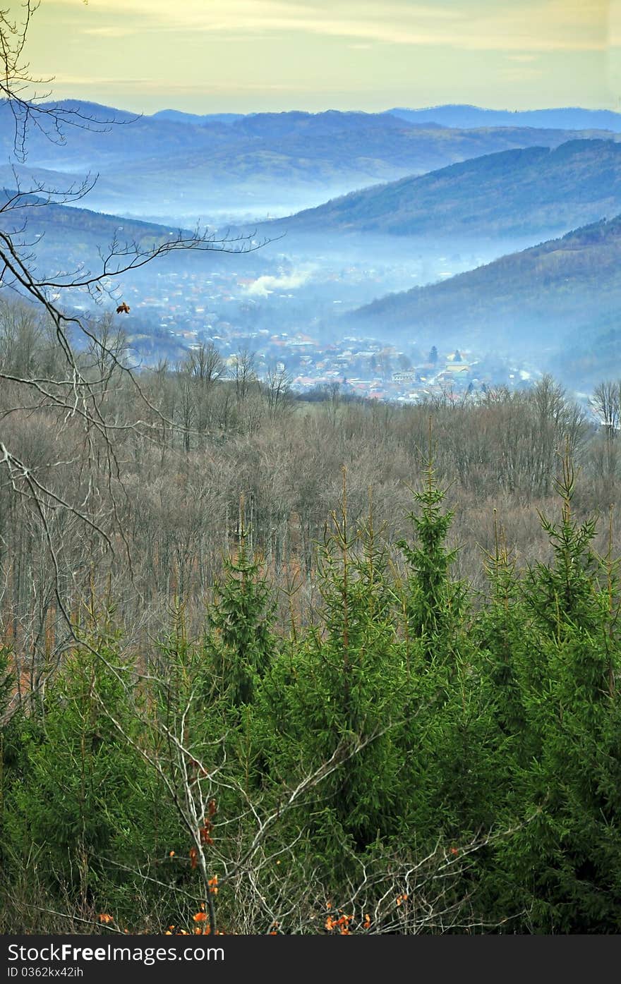 Fog over valley village in high mountains near alpine forest