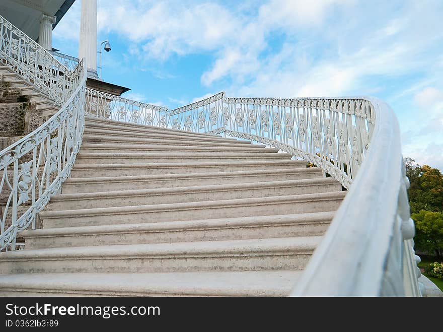 Marble old-fashioned stairway with handrails on the sky background