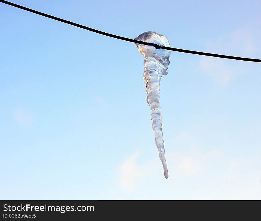 Brilliant icicle on electric wire in winter against the blue sky. Brilliant icicle on electric wire in winter against the blue sky