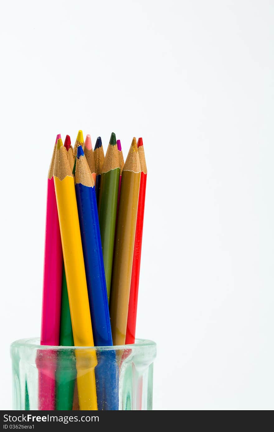 Colored pencils standing in an antique glass jar against a white background