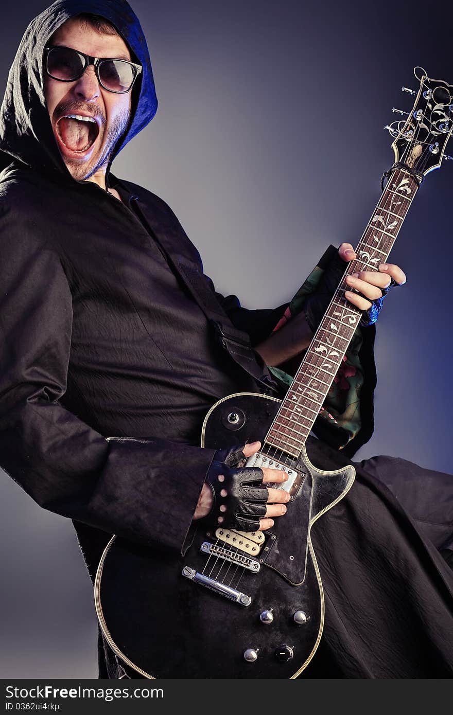 Heavy metal musician is playing electrical guitar. Shot in a studio. Heavy metal musician is playing electrical guitar. Shot in a studio.