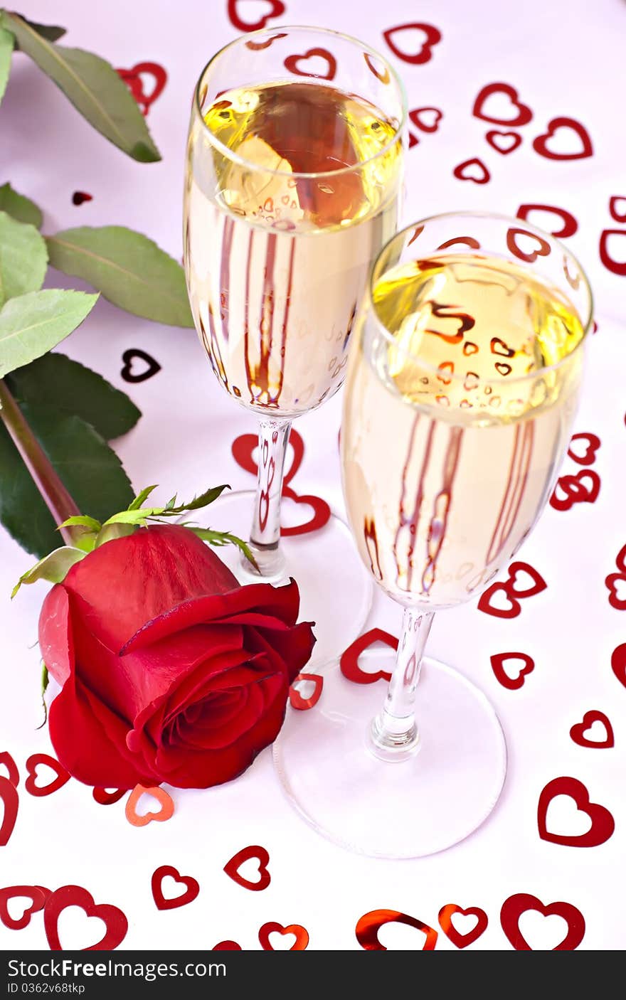 Beautifull red rose with two glasses of champagne on the pink surface with red hearts. Beautifull red rose with two glasses of champagne on the pink surface with red hearts.