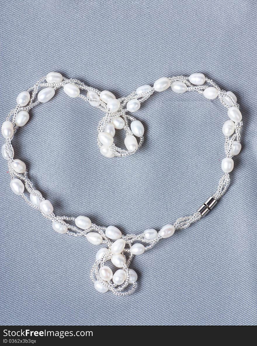 Heart-shaped string with pearls on a gray cloth. Heart-shaped string with pearls on a gray cloth