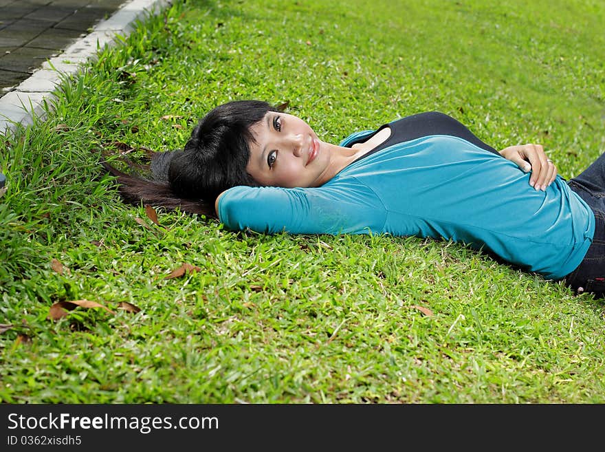 Young beautiful girl smiling and lying down on grass