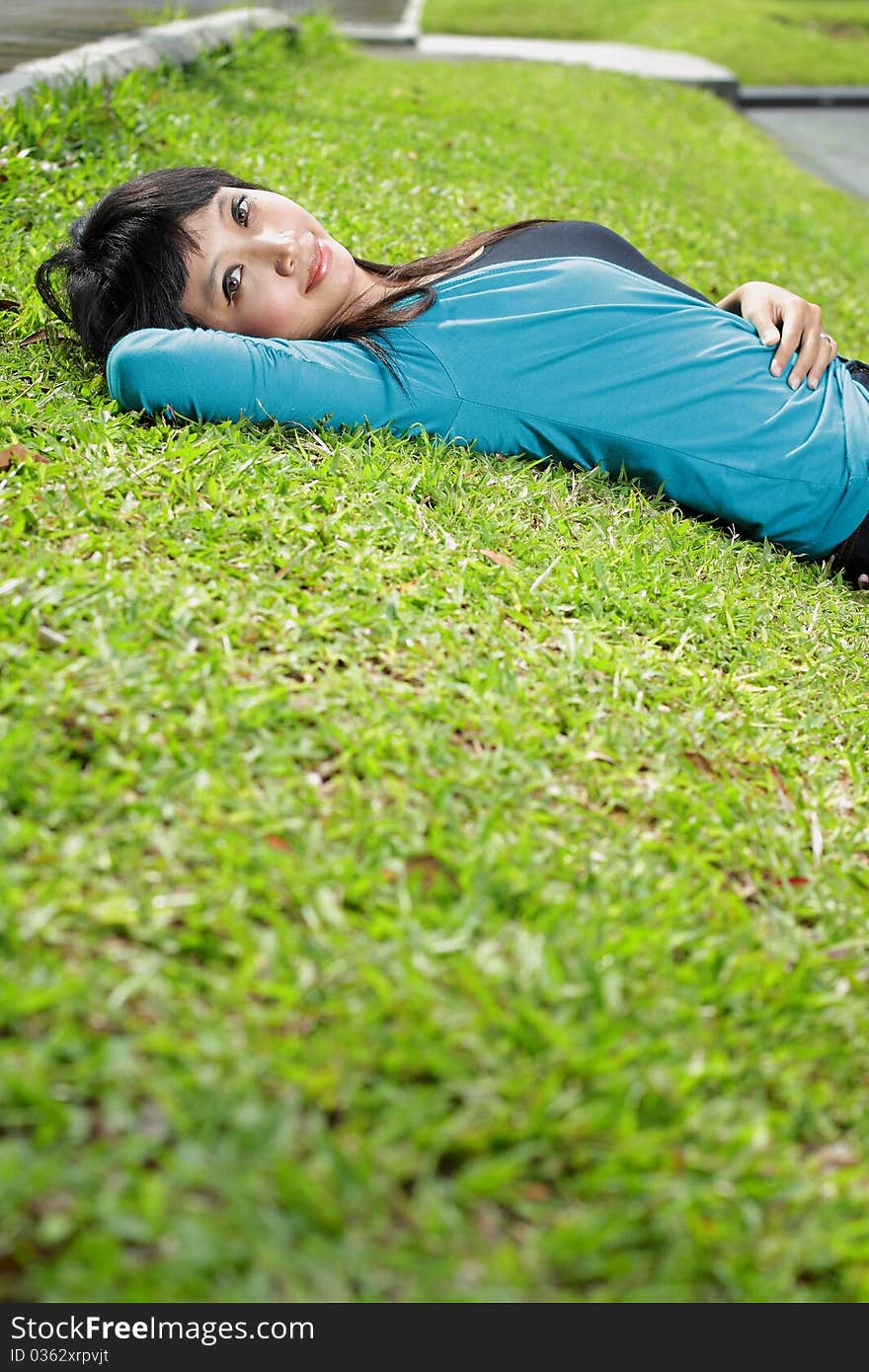 Young beautiful girl smiling and lying down on grass