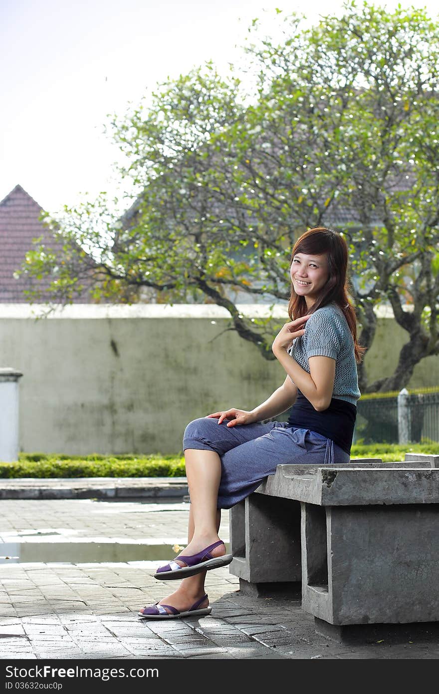 Young beautiful girl sitting in the park and smiling. Young beautiful girl sitting in the park and smiling