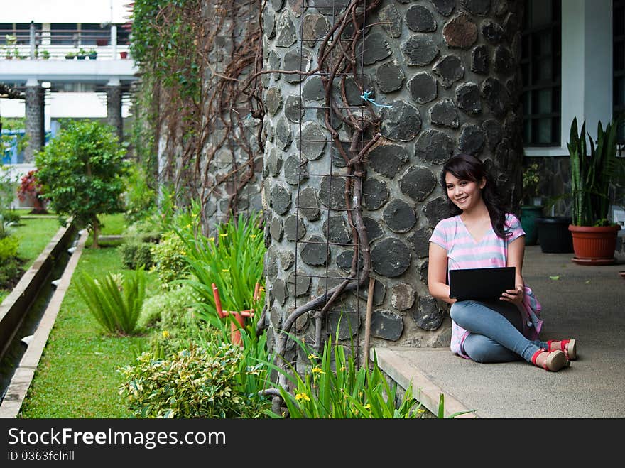 A happy female college student is working in university's park. A happy female college student is working in university's park