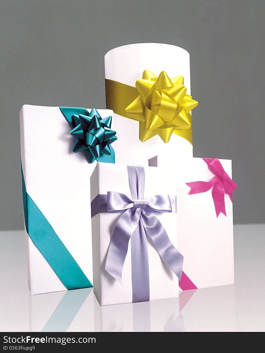 Four presents wrapped in white paper and bound with colorful bows and ribbons. Four presents wrapped in white paper and bound with colorful bows and ribbons.