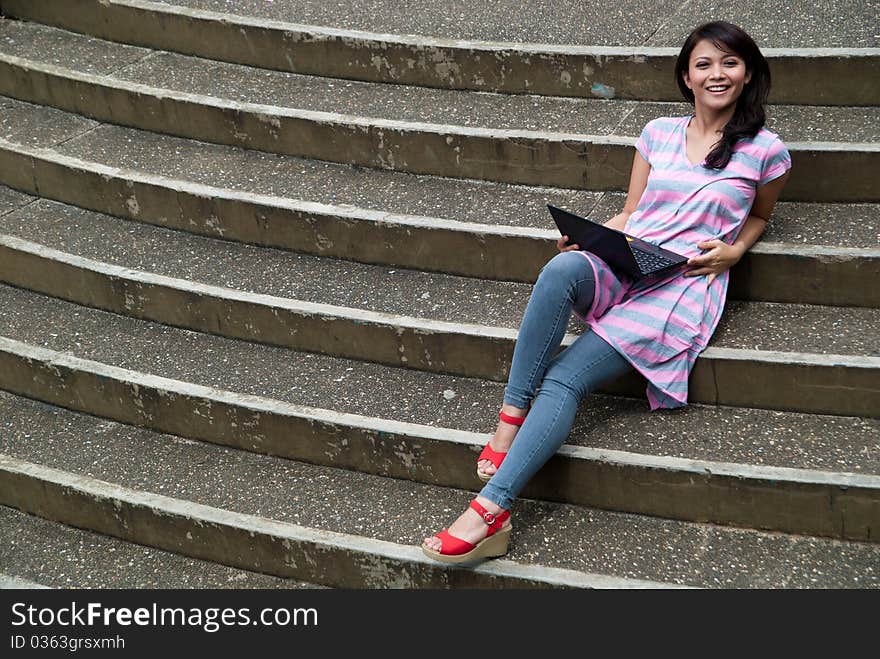 A happy female college student is working in university's park. A happy female college student is working in university's park