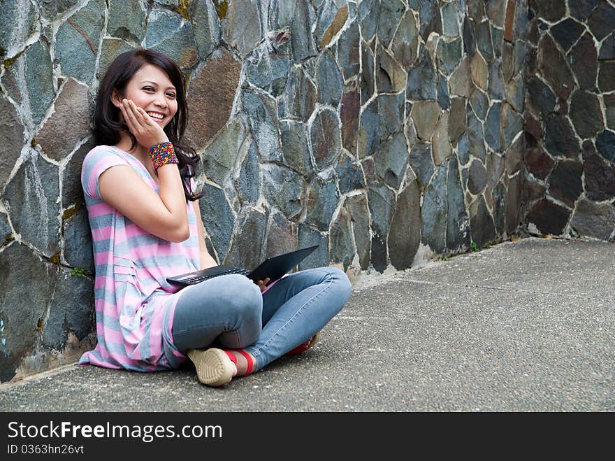 A happy female college student is working in university's park. A happy female college student is working in university's park