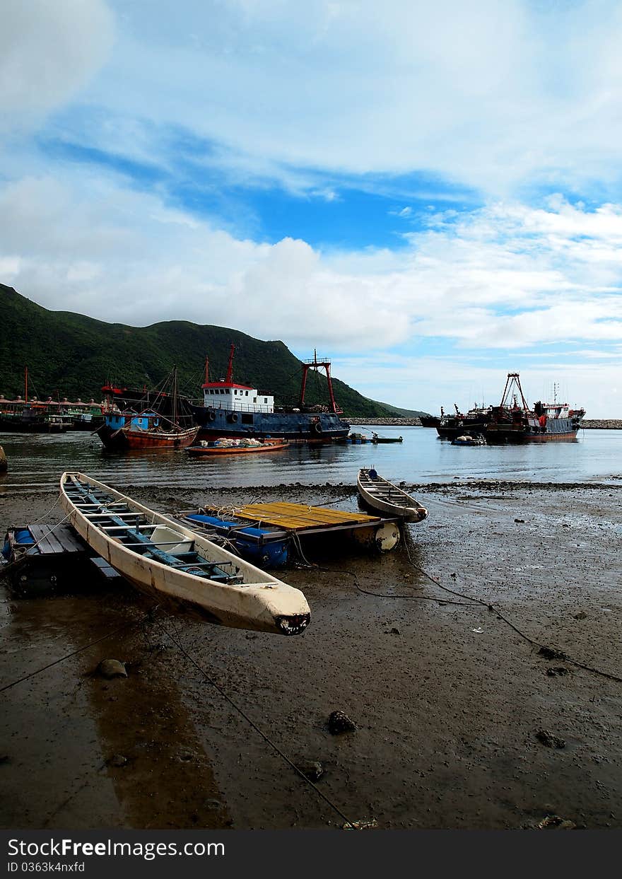 The rowing boat and fishing ships park on beach and dock