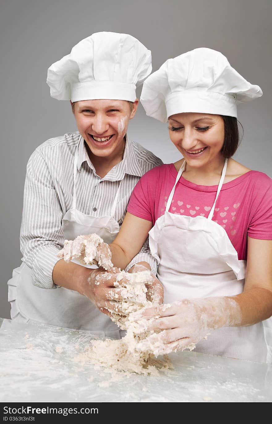 Young loving couple playing with dough. Over grey background