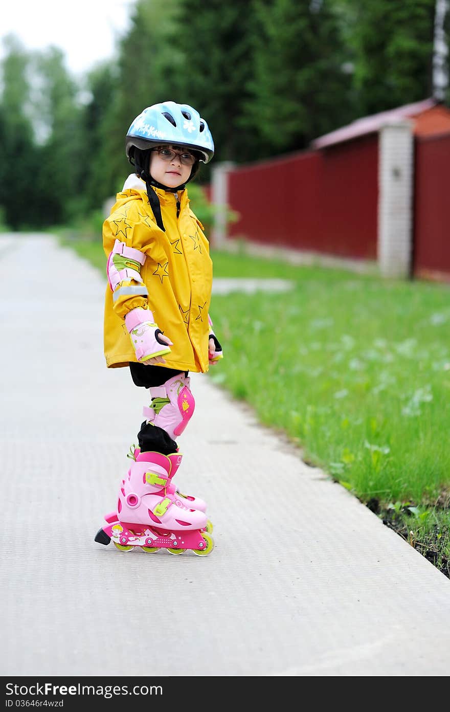 Adorable little girl in yellow raincoat, blue helmet and pink roller skates. Adorable little girl in yellow raincoat, blue helmet and pink roller skates