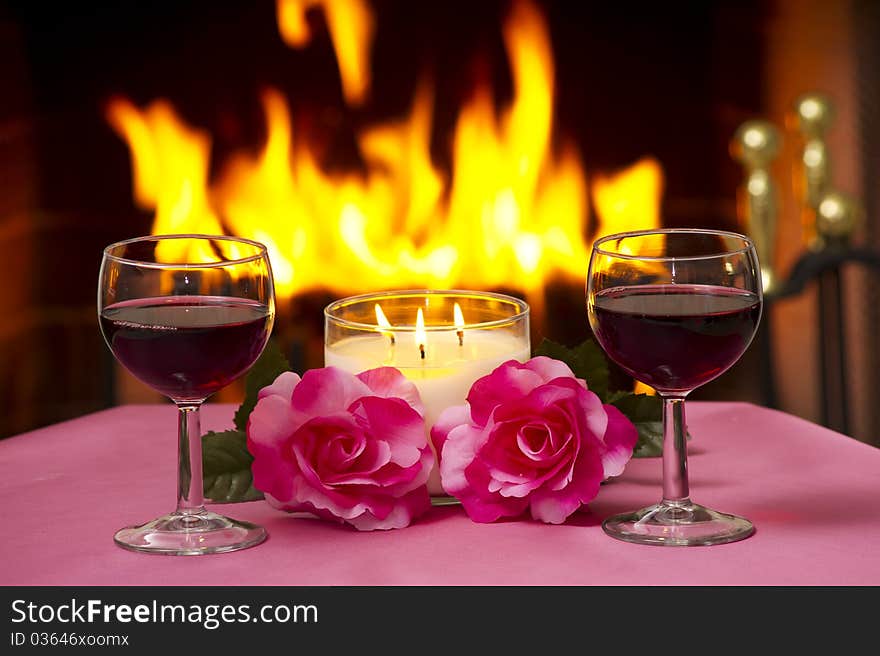 Two glasses of wine on a table with a fireplace in the background. Two glasses of wine on a table with a fireplace in the background.