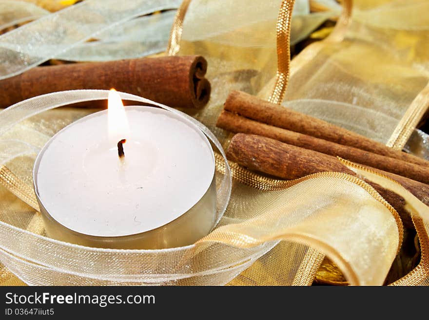 Candle on random background with ribbons and cinnamon. Candle on random background with ribbons and cinnamon