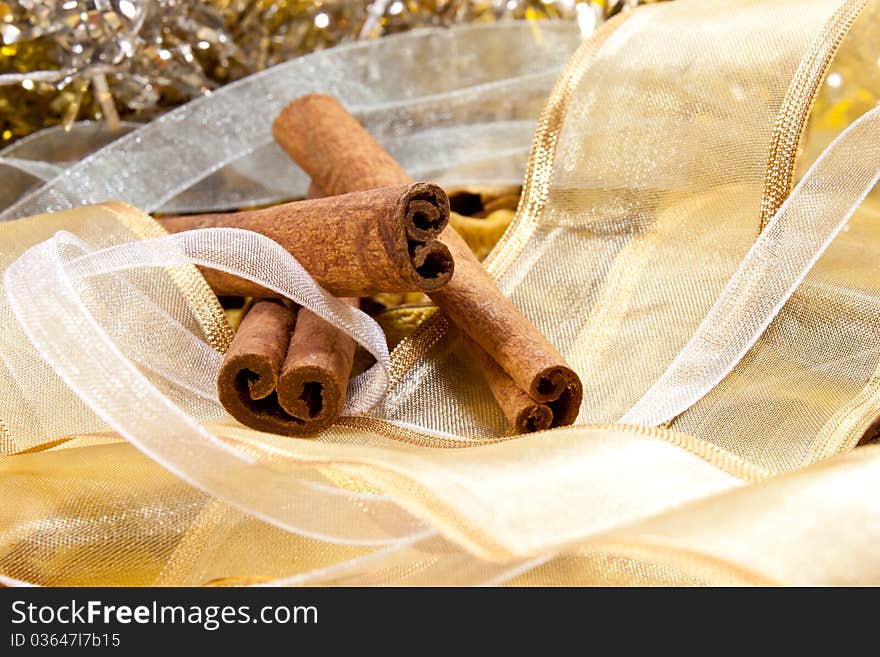 Cinnamon on random background with white and gold ribbons. Cinnamon on random background with white and gold ribbons