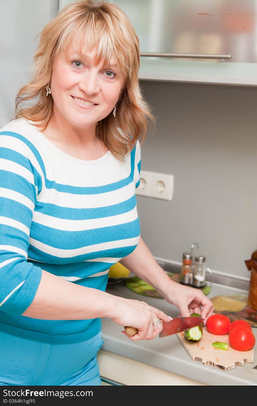 Beautiful woman in the kitchen cutting vegetables. Beautiful woman in the kitchen cutting vegetables