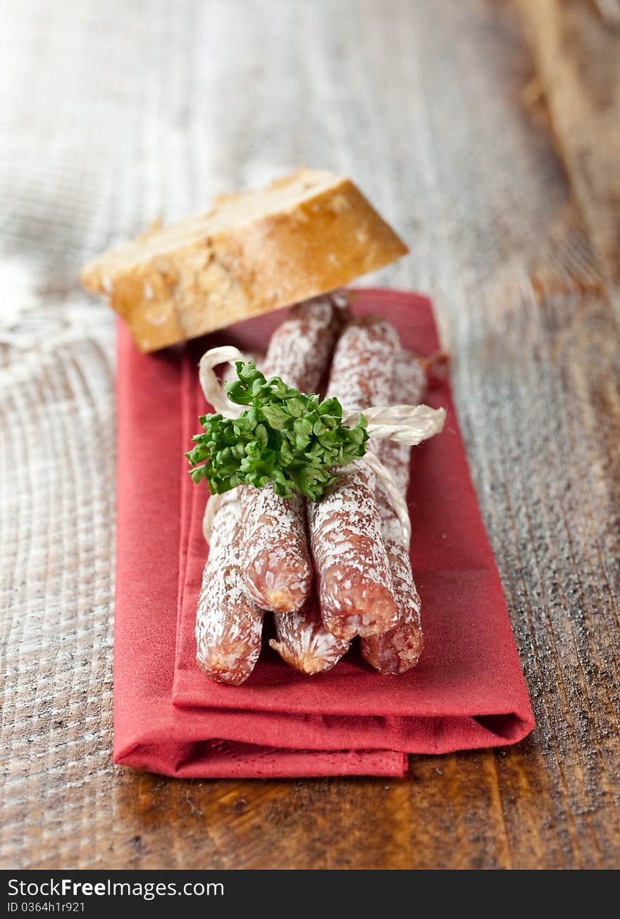 Small salamis on napkin with bread (country style)