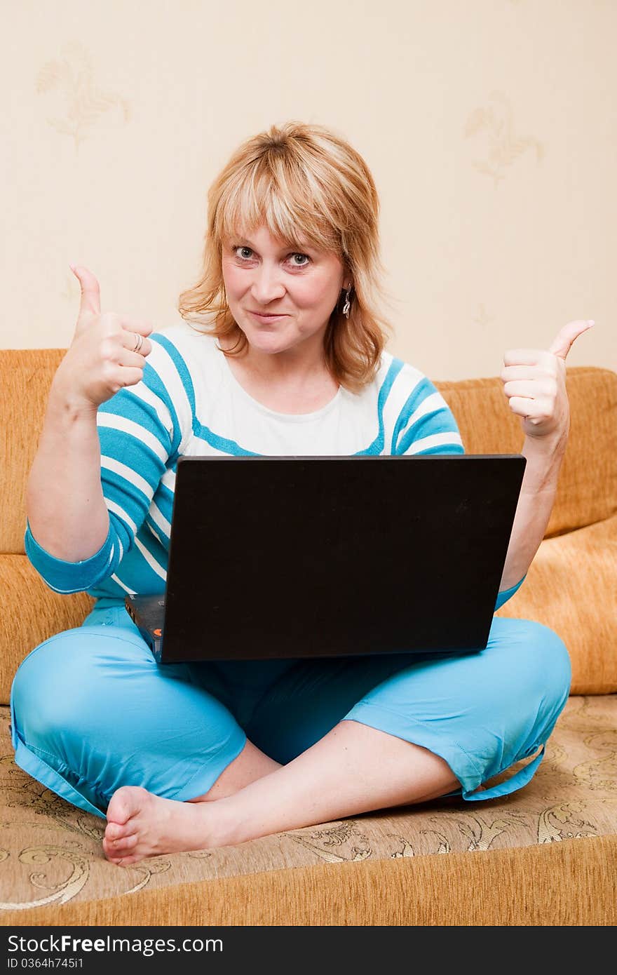 Successful woman using a laptop sitting on a sofa in the living-room. Successful woman using a laptop sitting on a sofa in the living-room