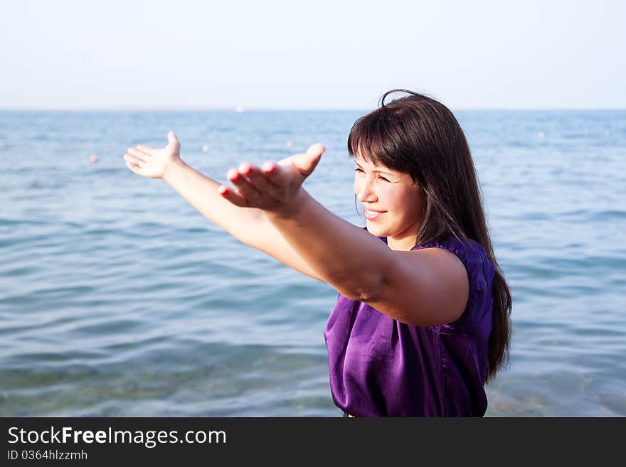 Beautiful young woman opened her hands with delight at the blue sky and sea. Beautiful young woman opened her hands with delight at the blue sky and sea