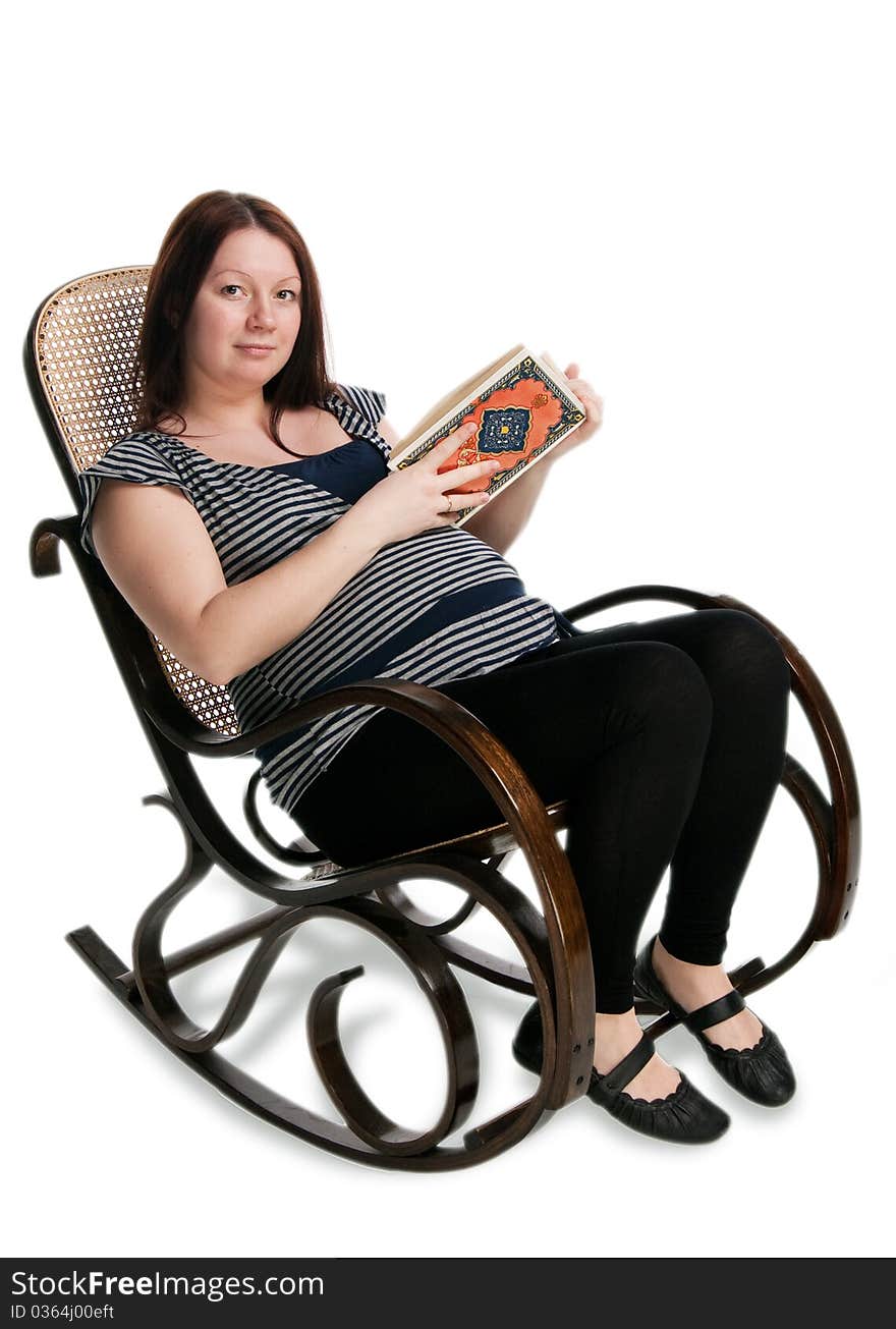 Pregnant woman reading a book in a rocking chair, isolated on white