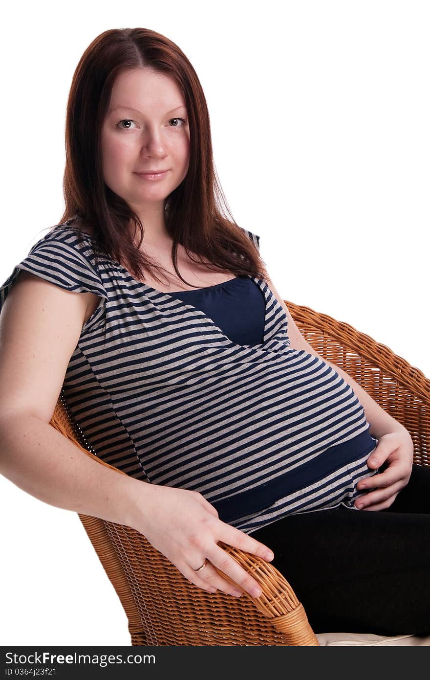 Pregnant woman sitting on a wicker chair , isolated on white