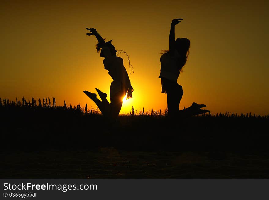 Two women in silhouette jumping happily in the sunset. Two women in silhouette jumping happily in the sunset