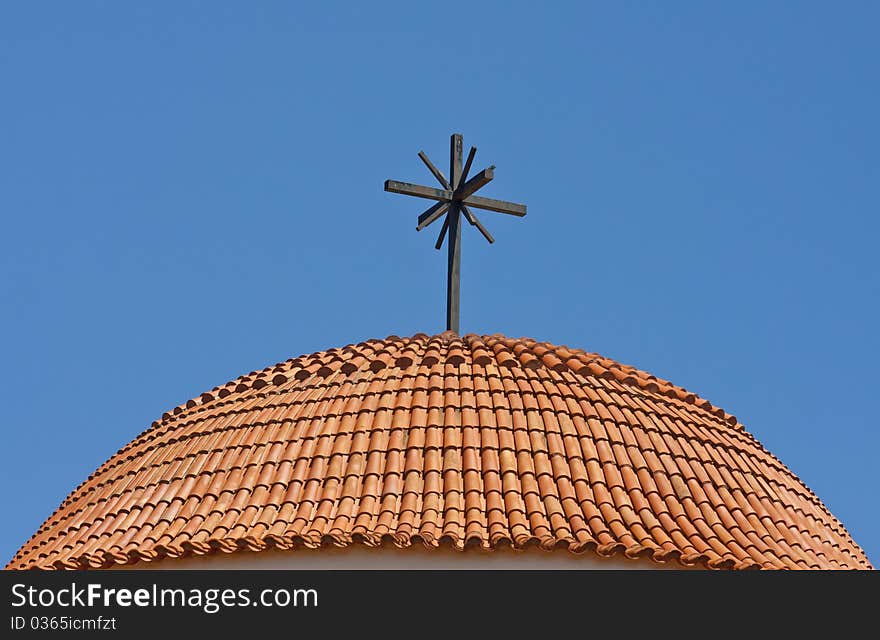 Round roof of a church - covered with tiles and cross