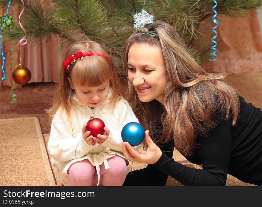 Mom and girl near christmas tree with balls. Mom and girl near christmas tree with balls