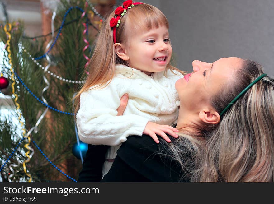 Happy mother and daughter near the Christmas Tree