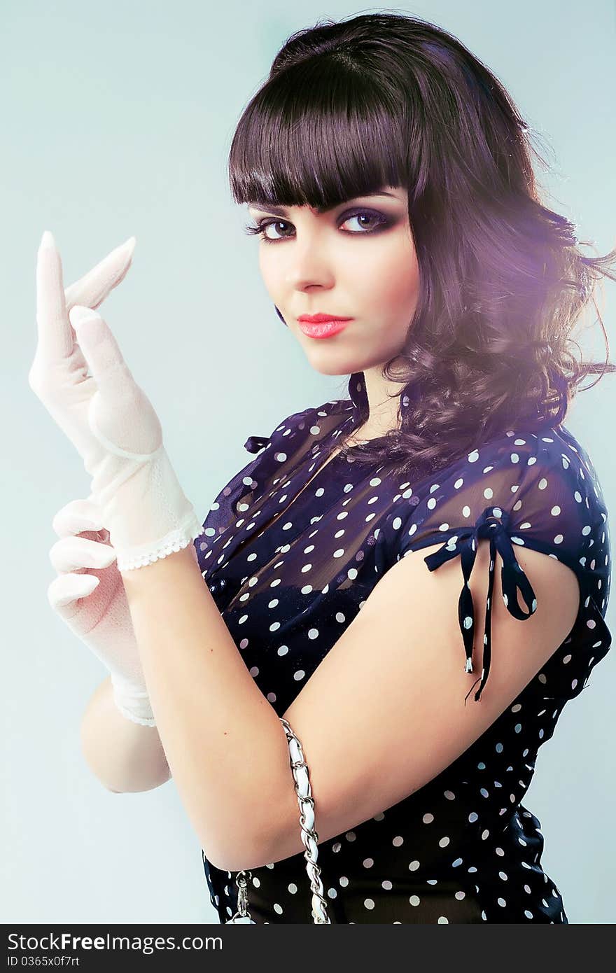 Studio portrait of a pretty elegant brunette dressing white gloves