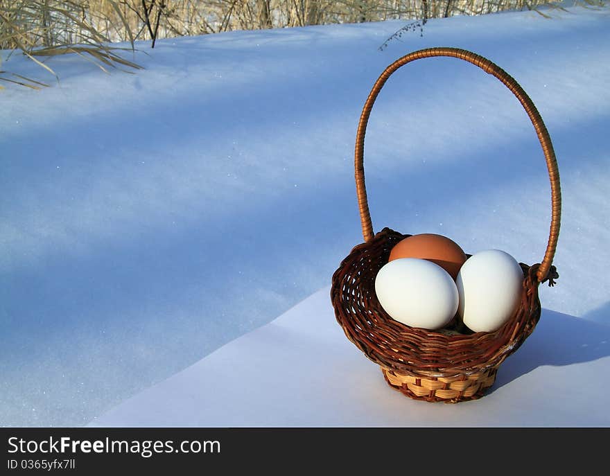 Three eggs in a basket on a background of a white snow