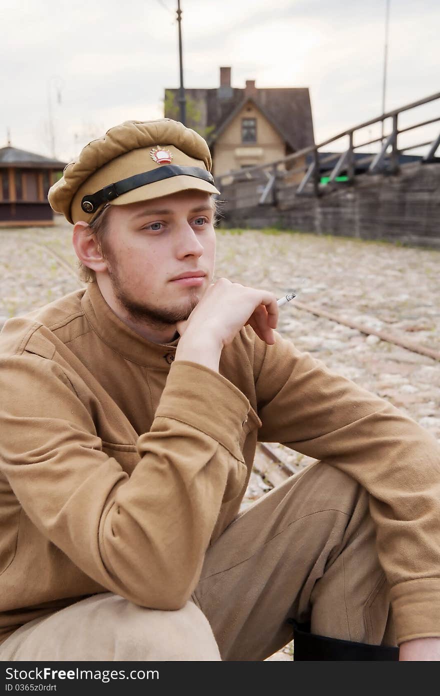 Soldier in uniform of World War I, sit down, resting on the pavement and smoking. Costume accord the times of World War I. Photo made at cinema city Cinevilla in Latvia. Cockade on the hat do not contain trade mark. Soldier in uniform of World War I, sit down, resting on the pavement and smoking. Costume accord the times of World War I. Photo made at cinema city Cinevilla in Latvia. Cockade on the hat do not contain trade mark.