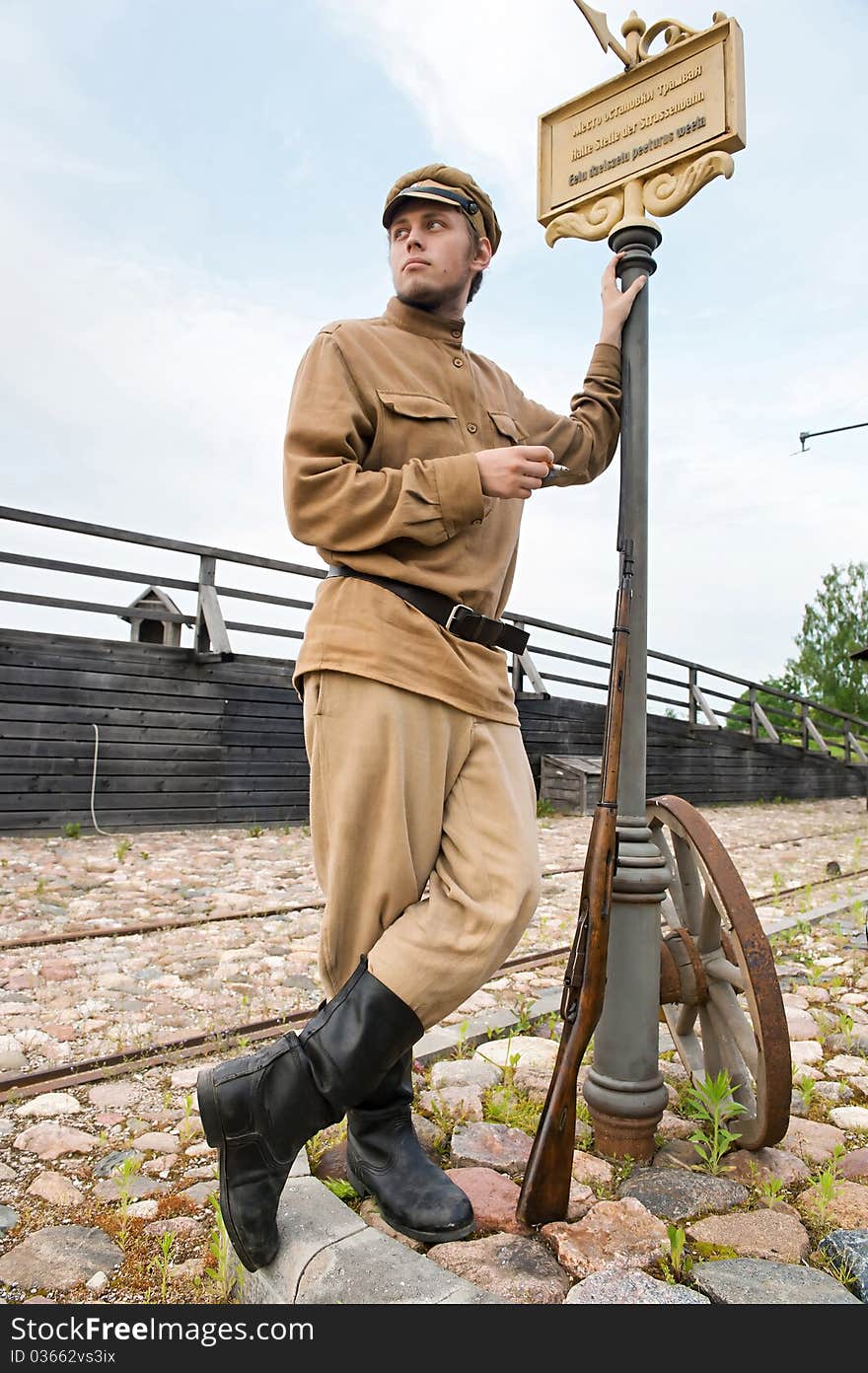 Soldier with a gun in uniform of World War I, smoking at tram stop. Costume accord the times of World War I. Photo made at cinema city Cinevilla in Latvia. Soldier with a gun in uniform of World War I, smoking at tram stop. Costume accord the times of World War I. Photo made at cinema city Cinevilla in Latvia.