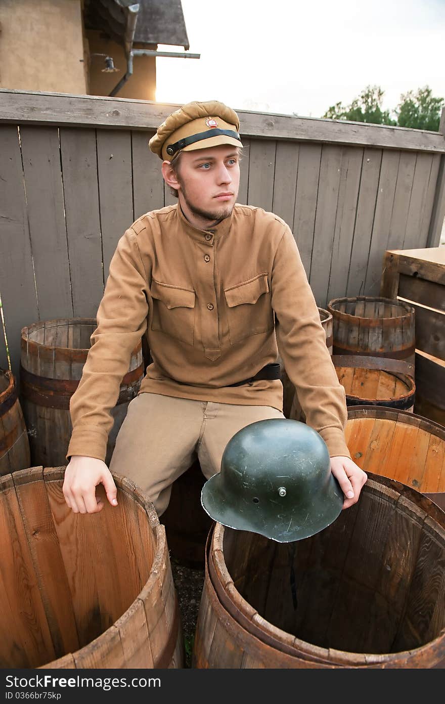 Soldier with a helmet sitting on the butt. Costume accord the times of World War I. Photo made at cinema city Cinevilla in Latvia. Soldier with a helmet sitting on the butt. Costume accord the times of World War I. Photo made at cinema city Cinevilla in Latvia.