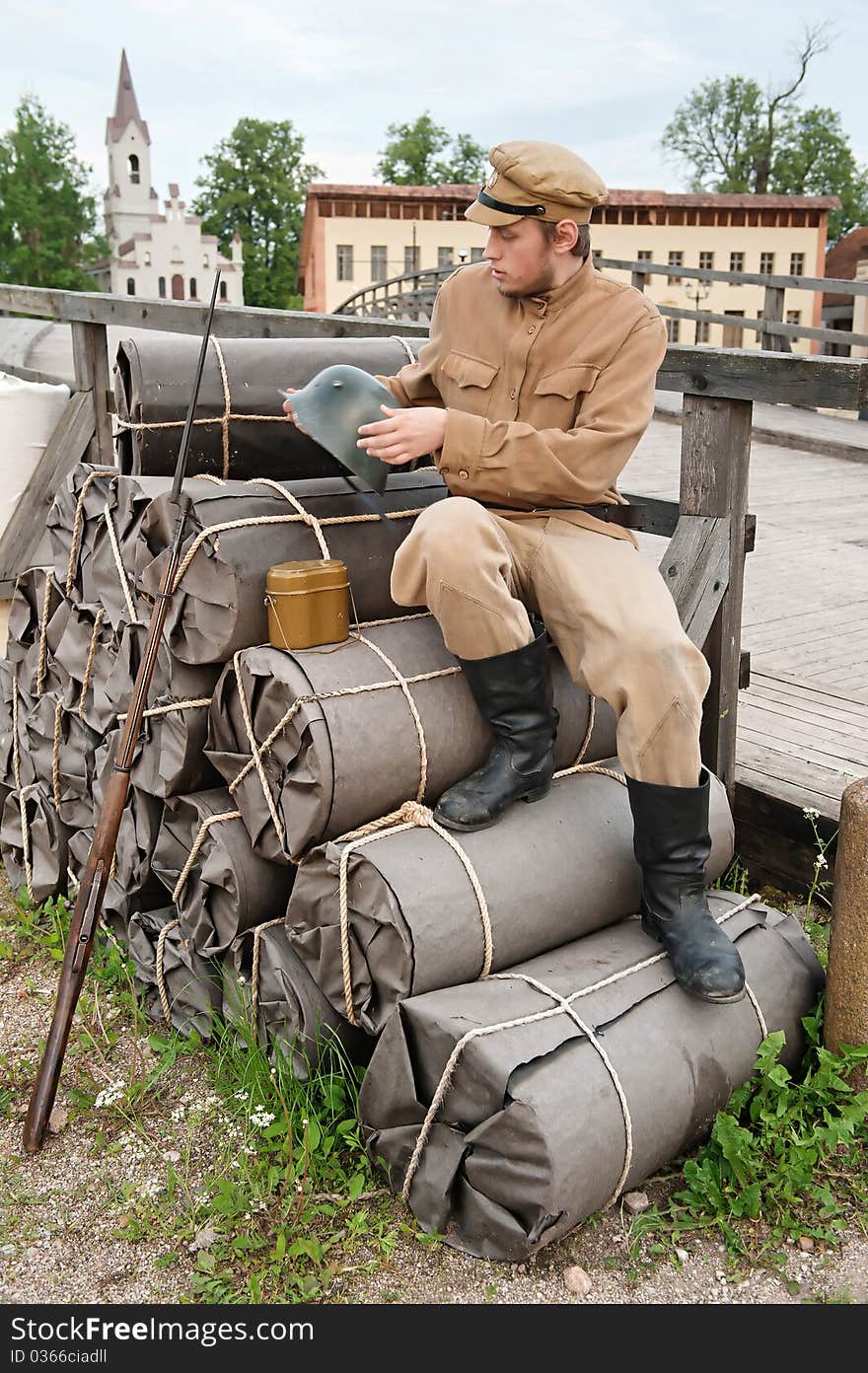 Soldier with helmet and gun sitting on the bundles. Costume accord the times of World War I. Photo made at cinema city Cinevilla in Latvia. Soldier with helmet and gun sitting on the bundles. Costume accord the times of World War I. Photo made at cinema city Cinevilla in Latvia.